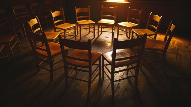 pusty krąg krzeseł w półmroku symbolizujący ciszę i obecność po spotkaniu mężczyzn